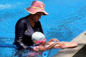Swimming trainer training a kid
